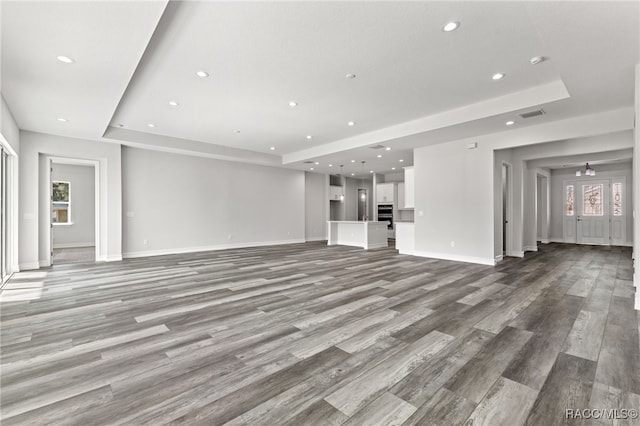 unfurnished living room with a tray ceiling and light hardwood / wood-style flooring