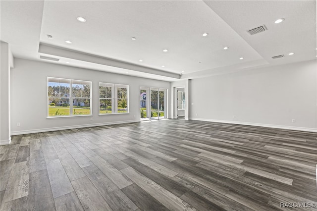 unfurnished living room with a raised ceiling and dark wood-type flooring