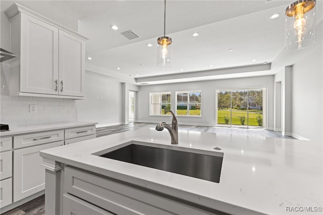 kitchen with decorative backsplash, dark wood-type flooring, sink, decorative light fixtures, and white cabinetry