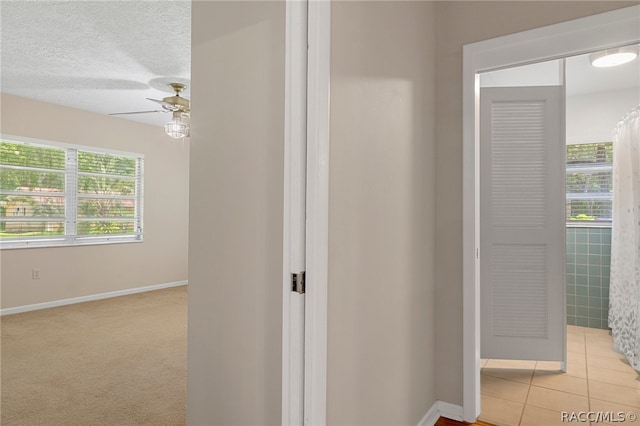 hall with light tile patterned floors, a textured ceiling, and tile walls