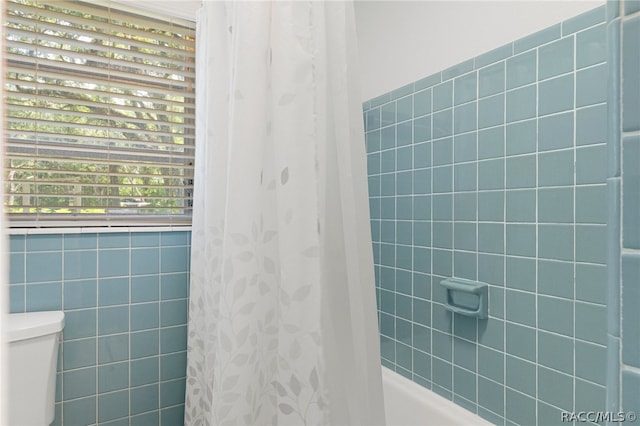 bathroom featuring toilet and shower / bathtub combination with curtain