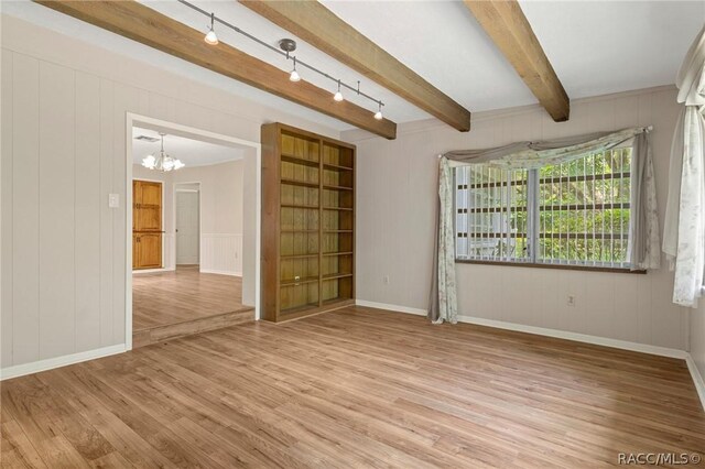 spare room with beamed ceiling, light wood-type flooring, and track lighting