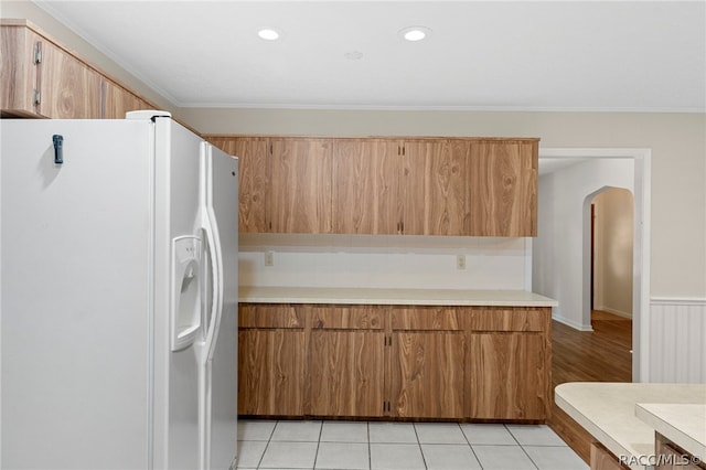 kitchen featuring light tile patterned floors, white fridge with ice dispenser, and ornamental molding