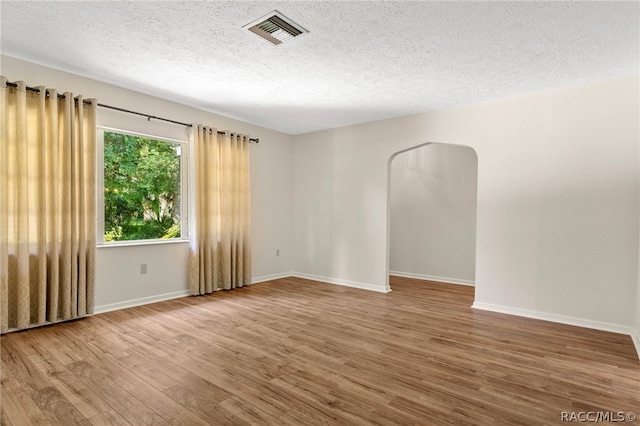 spare room featuring hardwood / wood-style flooring and a textured ceiling