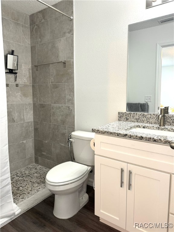 bathroom with wood-type flooring, vanity, toilet, and curtained shower