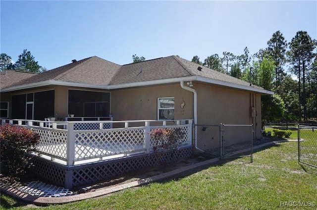 back of property with a sunroom and a lawn