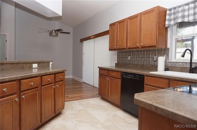 kitchen with backsplash, ceiling fan, sink, black dishwasher, and lofted ceiling