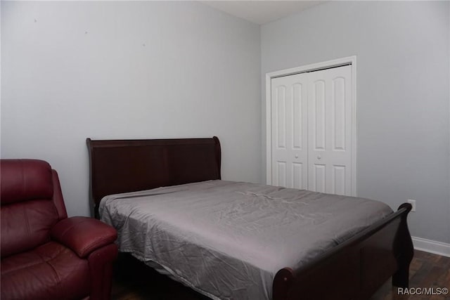 bedroom with dark hardwood / wood-style floors and a closet