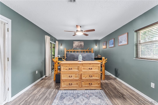 bedroom with ceiling fan, dark hardwood / wood-style flooring, and a textured ceiling