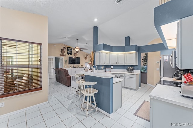 kitchen featuring a kitchen bar, kitchen peninsula, stainless steel appliances, ceiling fan, and light tile patterned floors