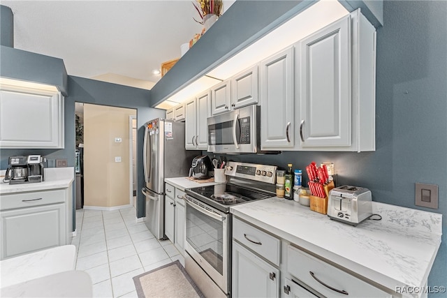 kitchen with white cabinets, light tile patterned floors, and appliances with stainless steel finishes