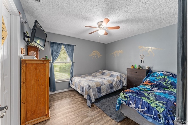 bedroom with ceiling fan, light hardwood / wood-style floors, and a textured ceiling