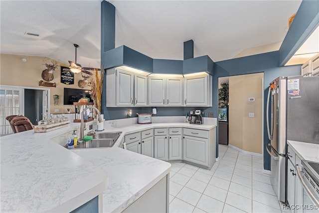 kitchen featuring sink, vaulted ceiling, light tile patterned floors, kitchen peninsula, and stainless steel appliances