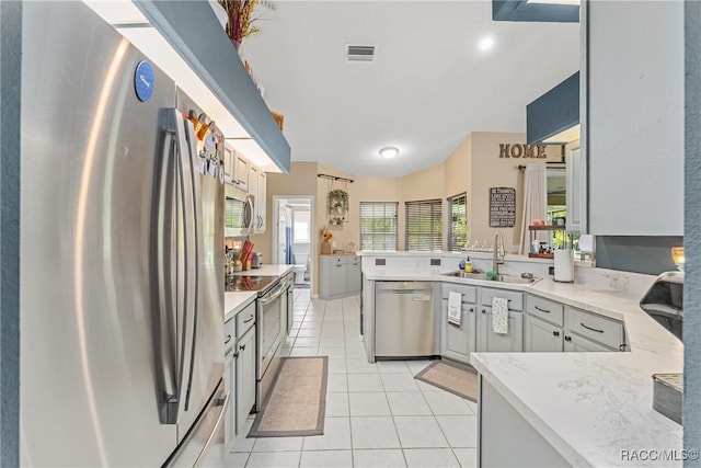 kitchen with appliances with stainless steel finishes, gray cabinets, light tile patterned floors, and sink