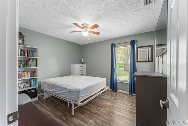 bedroom with a textured ceiling, ceiling fan, and dark wood-type flooring