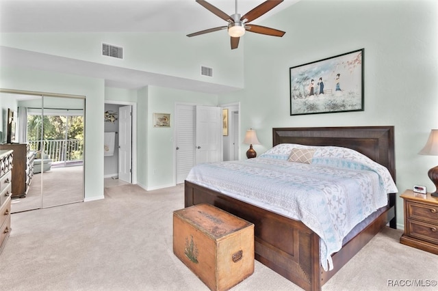 carpeted bedroom with ceiling fan, high vaulted ceiling, and multiple closets