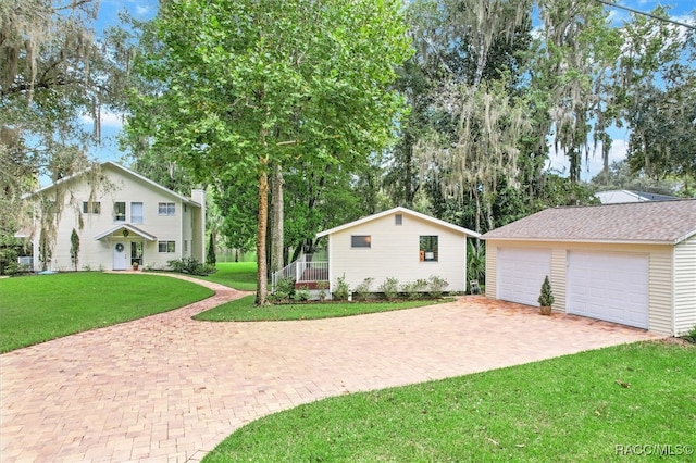 view of front facade featuring a garage, an outdoor structure, and a front lawn