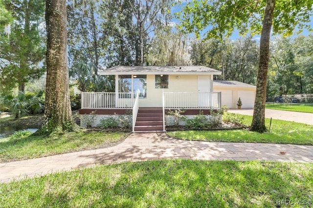 view of front of house featuring a garage, a front yard, and a porch