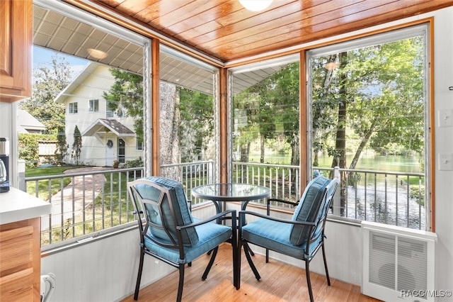 sunroom featuring a water view and wooden ceiling