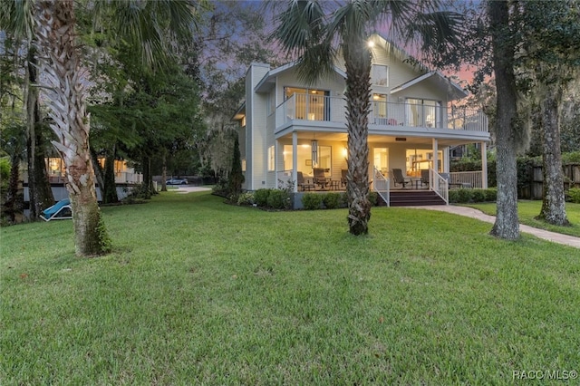 exterior space with covered porch, a balcony, and a lawn