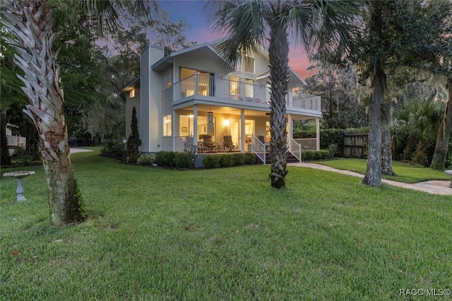 view of front of home featuring a porch, a balcony, and a yard