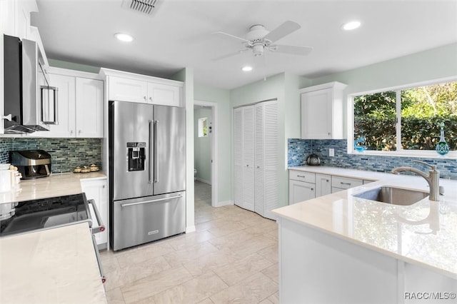 kitchen featuring sink, ceiling fan, white cabinetry, backsplash, and stainless steel appliances