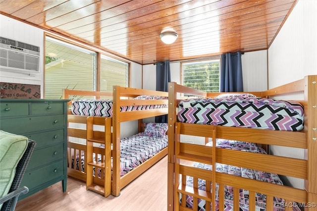 bedroom with a wall unit AC, hardwood / wood-style floors, and wooden ceiling