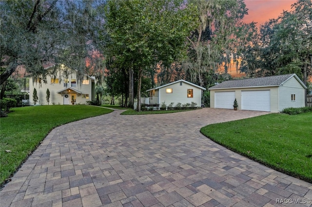 view of front of home featuring a garage, an outbuilding, and a lawn