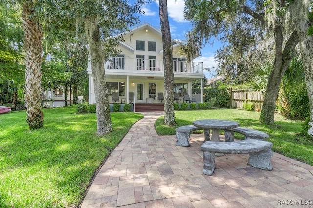 view of front of house with a front yard, a patio, a balcony, and a porch