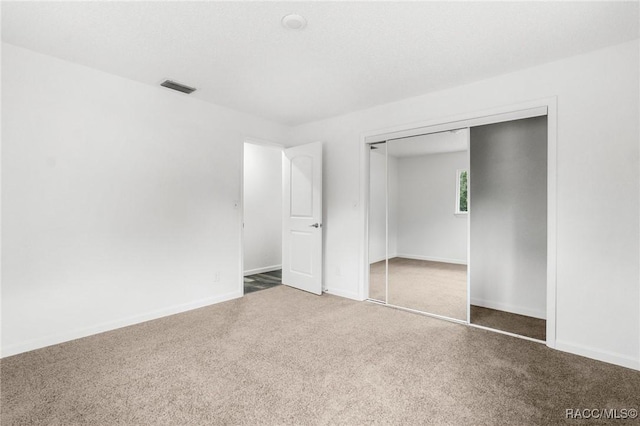 unfurnished bedroom with dark carpet and a closet