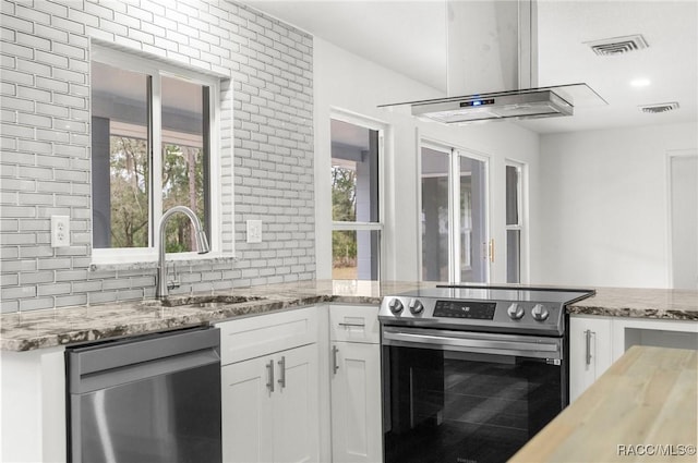 kitchen with stainless steel appliances, light stone countertops, sink, and white cabinets