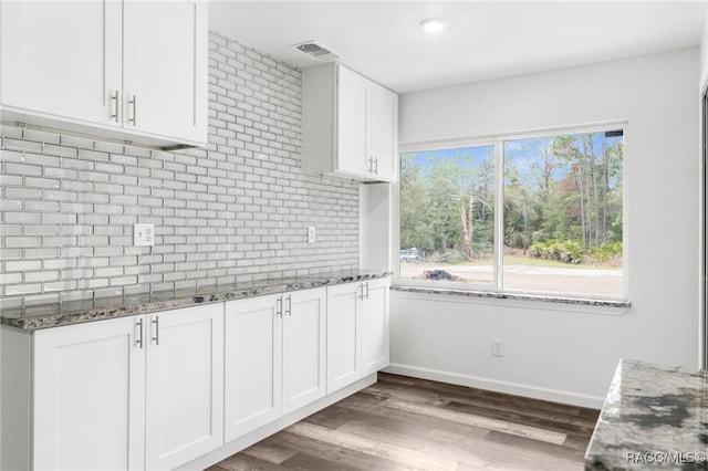 kitchen featuring white cabinetry, wood-type flooring, dark stone counters, and tasteful backsplash