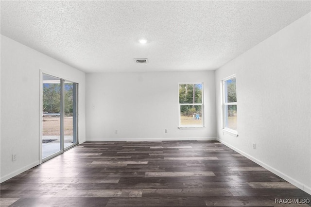 spare room featuring a healthy amount of sunlight, dark hardwood / wood-style flooring, and a textured ceiling