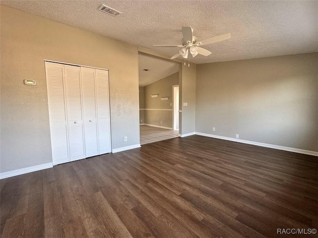 unfurnished bedroom with ceiling fan, a textured ceiling, dark hardwood / wood-style flooring, vaulted ceiling, and a closet