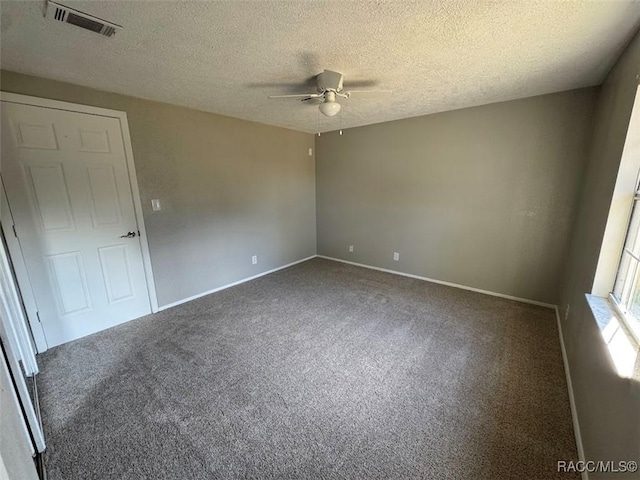 unfurnished room featuring ceiling fan, dark carpet, and a textured ceiling