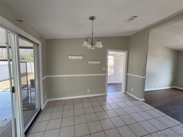 spare room featuring vaulted ceiling, light tile patterned flooring, a textured ceiling, and a chandelier