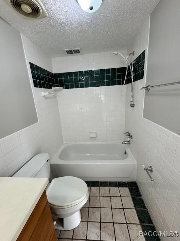 full bathroom featuring vanity, toilet, tile walls, and a textured ceiling