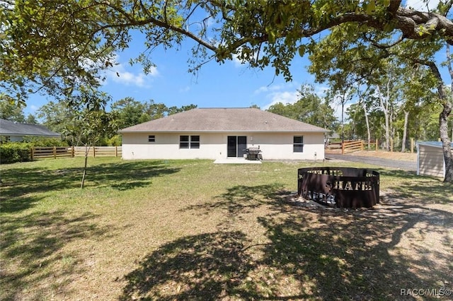 rear view of house with a yard, stucco siding, and fence
