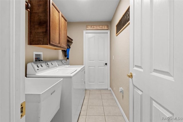 clothes washing area with light tile patterned floors, baseboards, washing machine and clothes dryer, and cabinet space