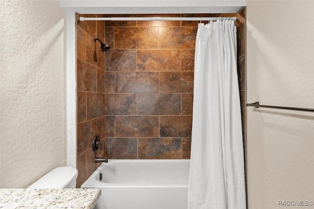 full bath featuring toilet, a textured wall, and shower / bath combo with shower curtain
