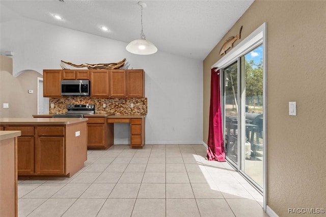 kitchen featuring lofted ceiling, stainless steel appliances, brown cabinets, decorative backsplash, and light countertops
