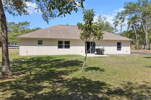 back of house featuring a yard, a patio area, and stucco siding