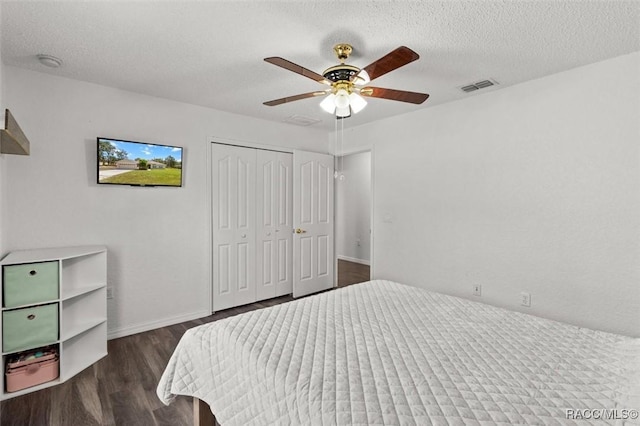bedroom with a closet, a textured ceiling, visible vents, and dark wood-style floors