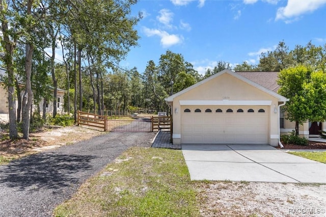view of front facade with a gate, a garage, stucco siding, fence, and concrete driveway