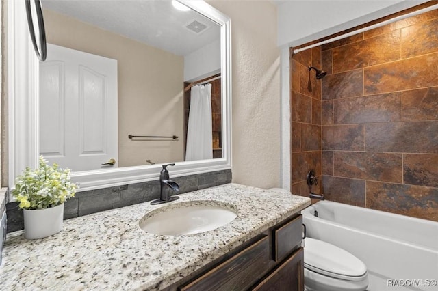 bathroom featuring toilet, vanity, shower / tub combo with curtain, visible vents, and a textured wall