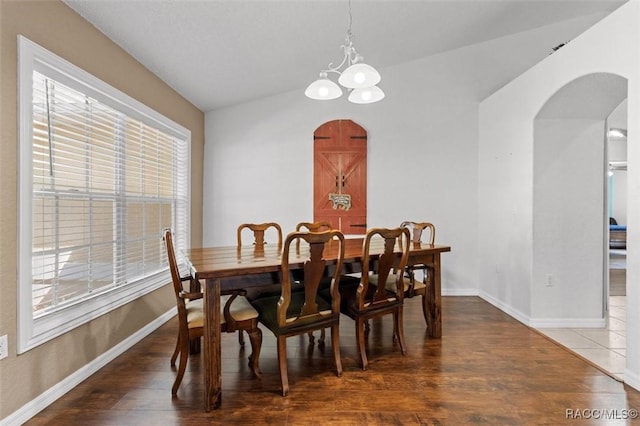 dining space with arched walkways, a wealth of natural light, and wood finished floors