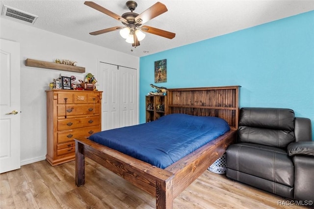 bedroom featuring a closet, baseboards, ceiling fan, visible vents, and wood finished floors