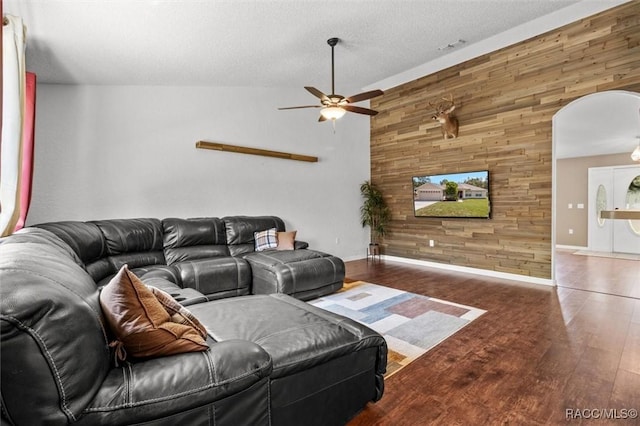 living area with baseboards, wooden walls, ceiling fan, and wood finished floors