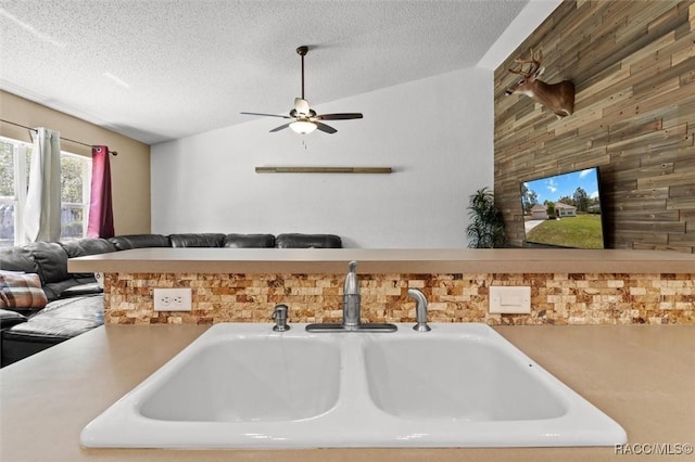 kitchen featuring a sink, a textured ceiling, vaulted ceiling, ceiling fan, and open floor plan