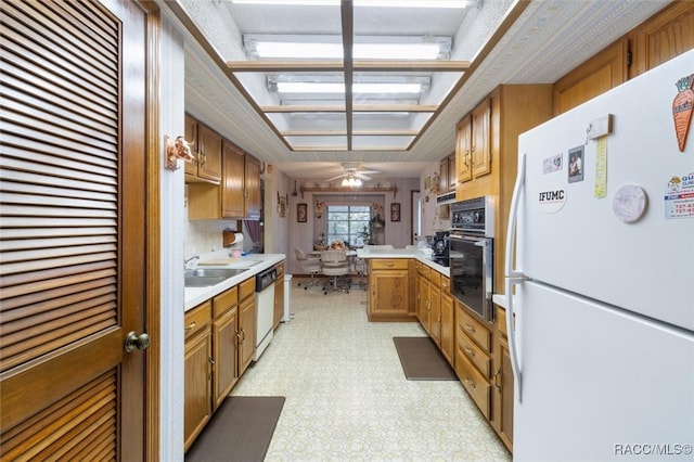 kitchen with kitchen peninsula, ceiling fan, sink, and white appliances